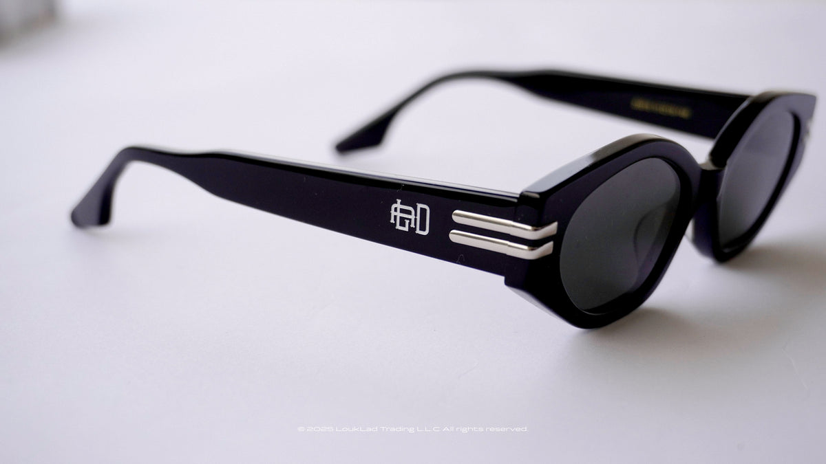Black sunglasses with a Engraved logo on a light gray background